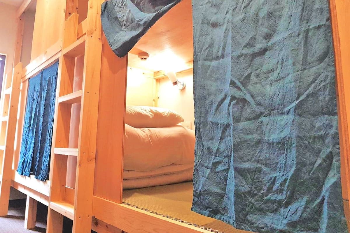 Una cama litera de madera con colchón y una manta azul.