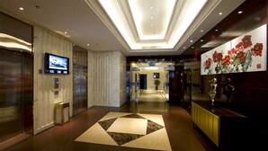 A hotel lobby with a modern design, featuring a large geometric patterned floor, a reception desk, and a television mounted on the wall. - HangZhou HuaYang Hotel (Hangzhou)