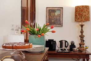 A dining table with a cake and tulips, a coffee maker, and a lamp. - Houspitality Caesar B&B (Rome)