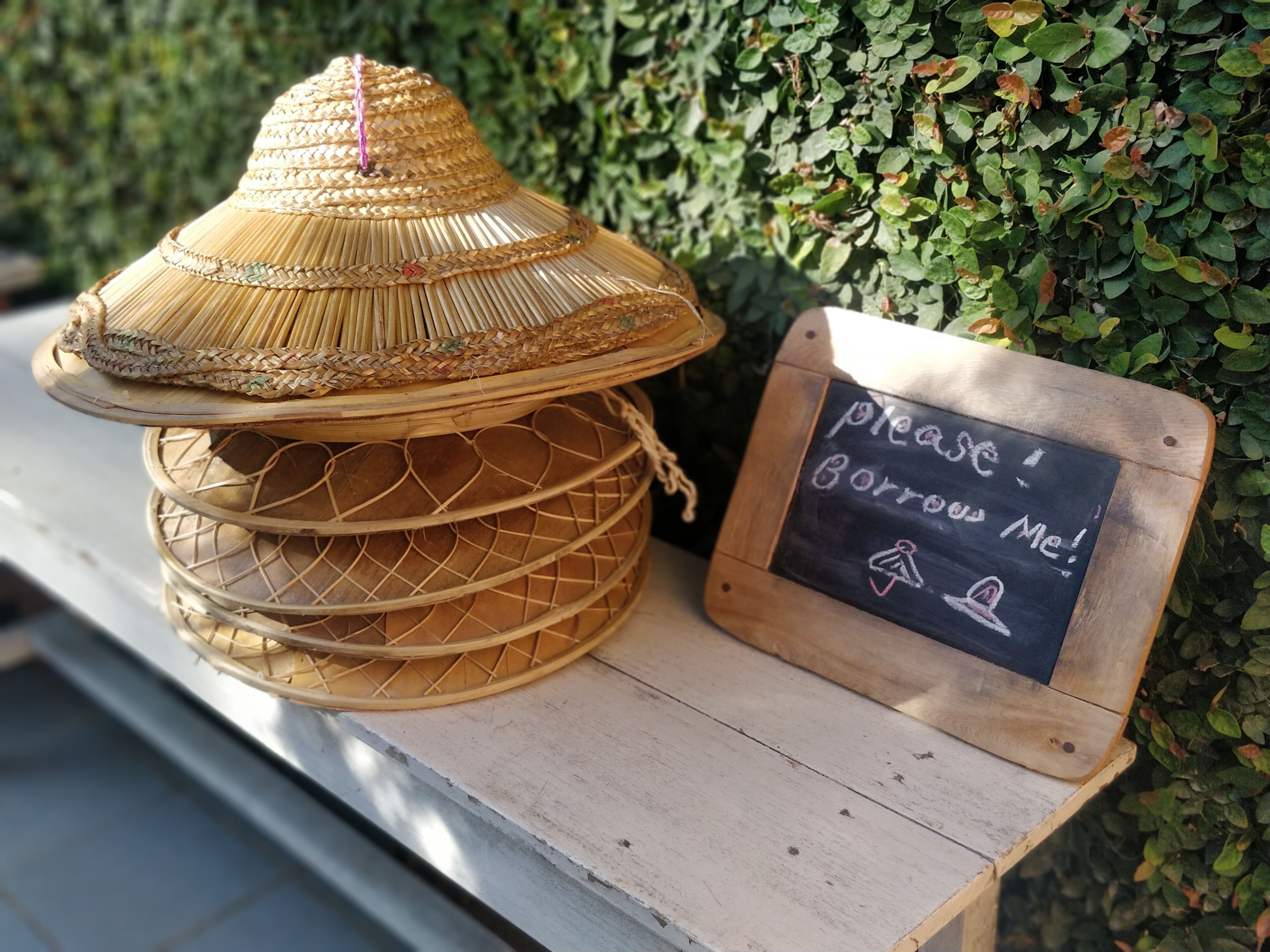 Un farol tejido tradicional con una tapa cónica y un letrero de pizarra al lado.