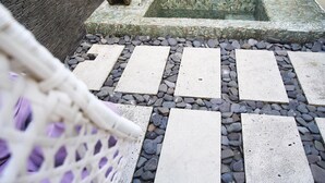 Un sendero de piedra que conduce a una fuente de agua con diseño de mosaico.