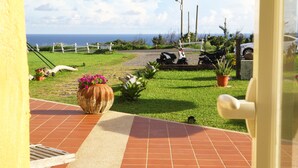 Un patio con suelo de baldosas, plantas en macetas y vista al océano.