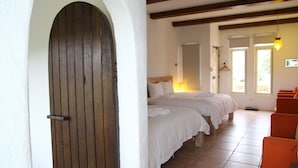 Habitación de hotel con dos camas, una puerta de madera, sillas color naranja y piso de baldosas.