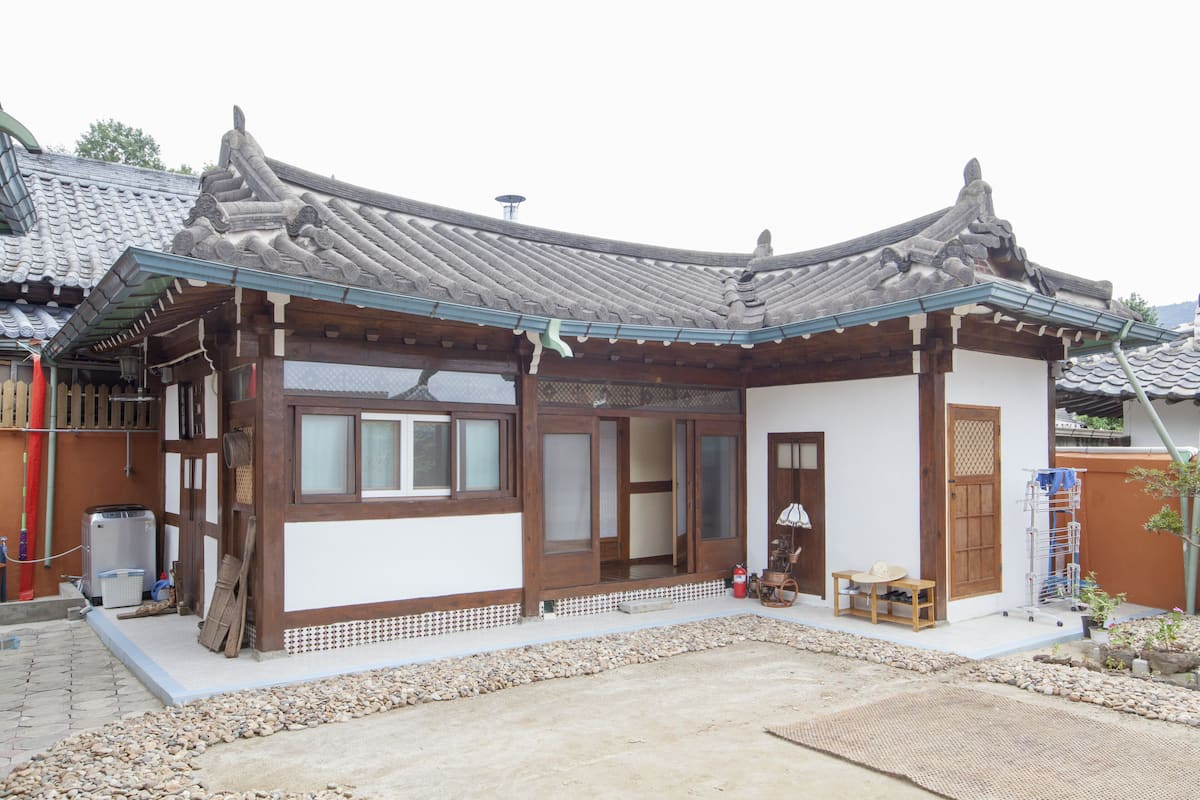 A traditional Japanese house with a tiled roof, wooden beams, and a small garden area.