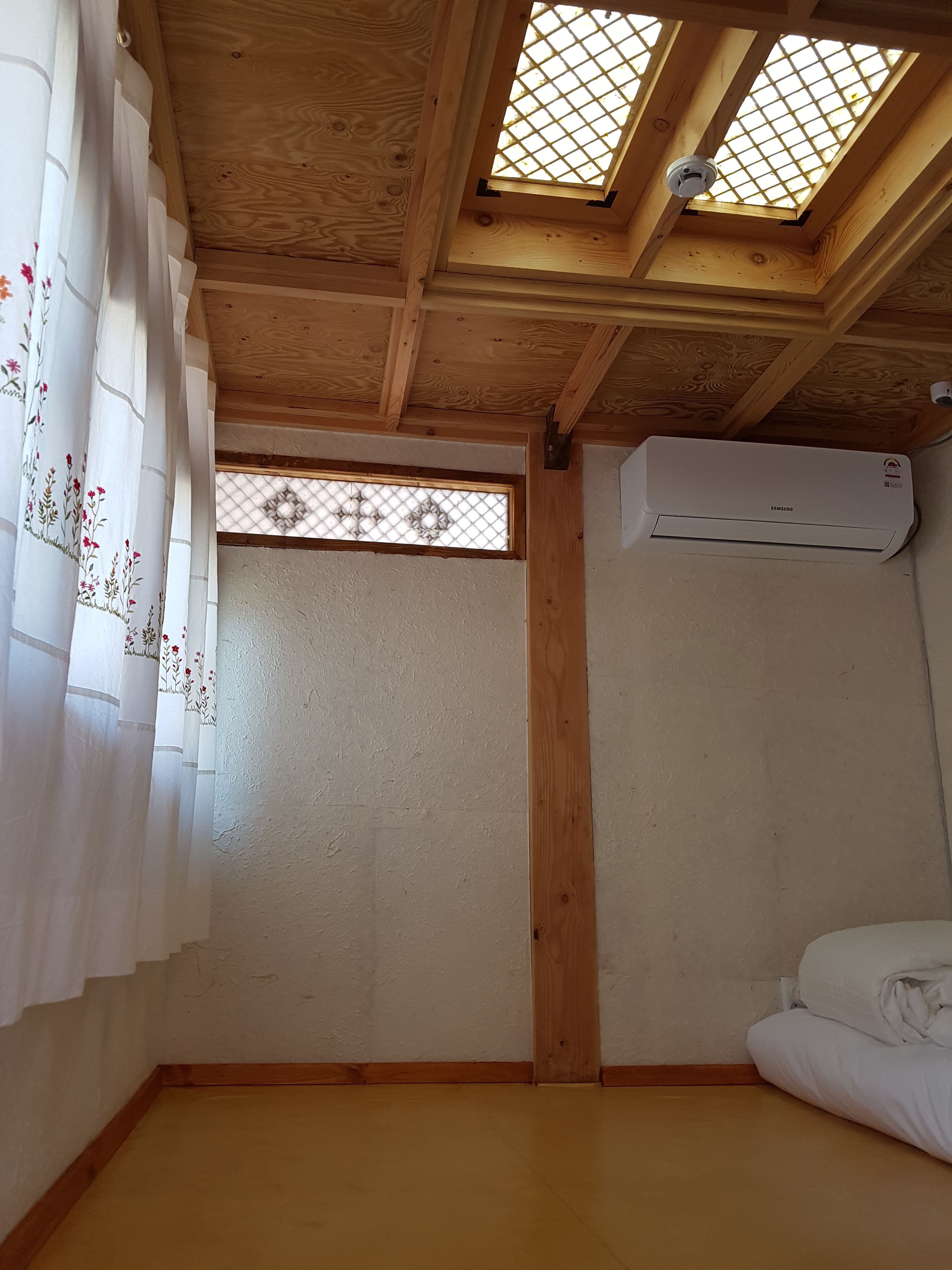 A room with a skylight, an air conditioning unit, and a bed.