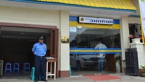 A building with a blue and yellow facade, a sign with a logo and text, and a person standing in front.