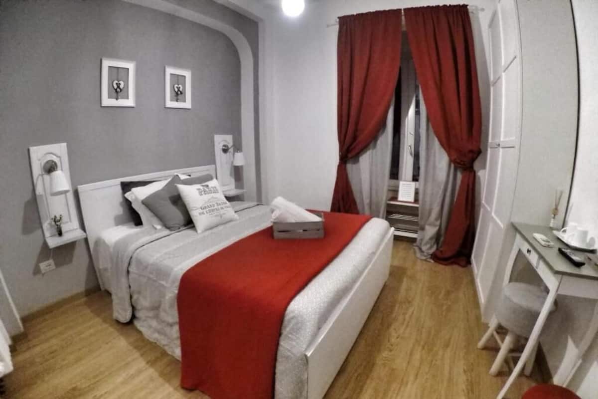 Une chambre à coucher avec un lit, un bureau et une chaise. Il y a deux tableaux encadrés accrochés au mur.