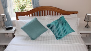 A bed with two pillows, a wooden headboard, and a bedside table with a lamp. - Magnolia B and B (Bristol)