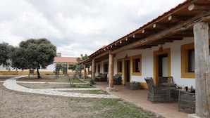 Un espacio al aire libre techado con mobiliario de mimbre y un sendero de piedra.