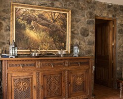 A wooden cabinet with intricate carvings, a framed painting of a forest scene, and decorative lanterns.