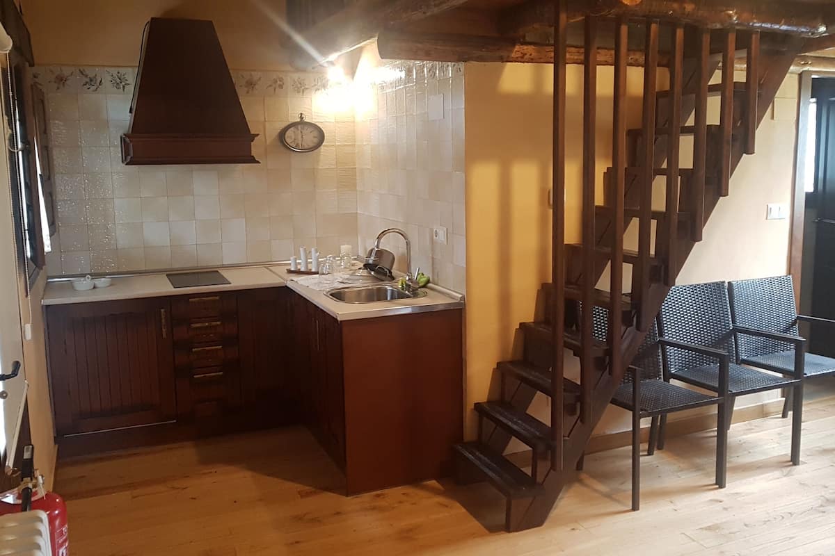 A kitchen with a wooden staircase, a sink, and a clock on the wall.