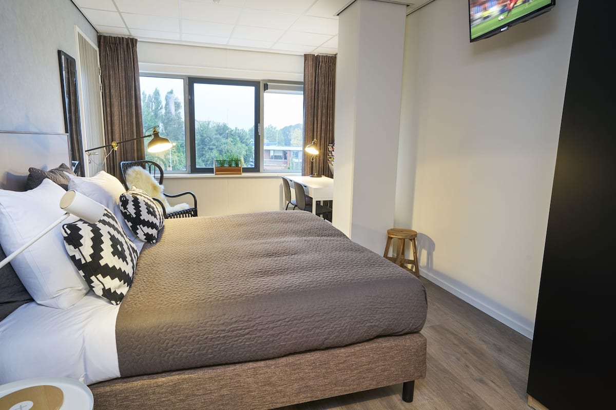 Un dormitorio moderno con una cama grande, un escritorio y una televisión.