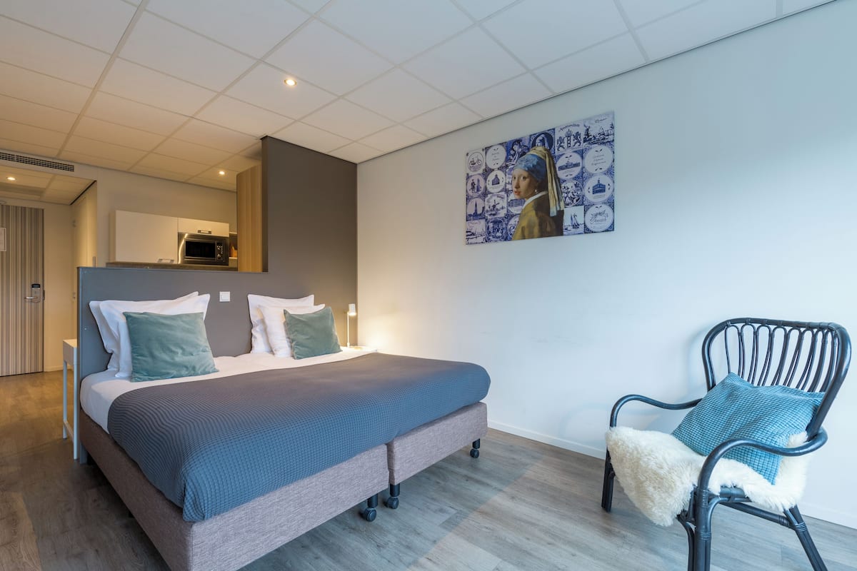 Un dormitorio moderno con cama, una silla y una obra de arte colgada en la pared.