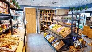 Ein Markt mit Lebensmitteln, Holzböden, verschiedenen verpackten Waren und einer Auswahl an frischem Obst und Gemüse.