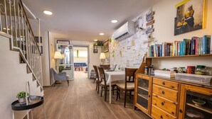 A dining area with a wooden table and chairs, a staircase, and a wall with notes and books. - Mike's House Jerusalem (Jerusalem)