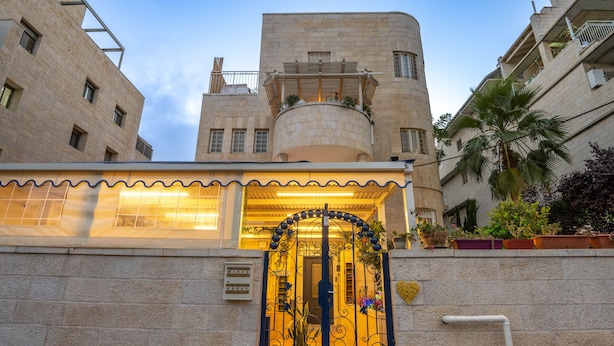 A building with a stone facade, a decorative wrought iron gate, and a balcony with plants. - Mike's House Jerusalem (Jerusalem)