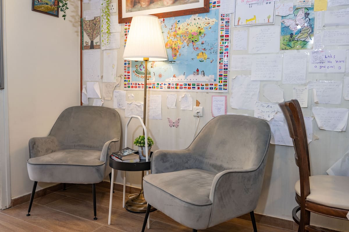 A room with two grey armchairs, a small side table with a lamp, and a world map on the wall.