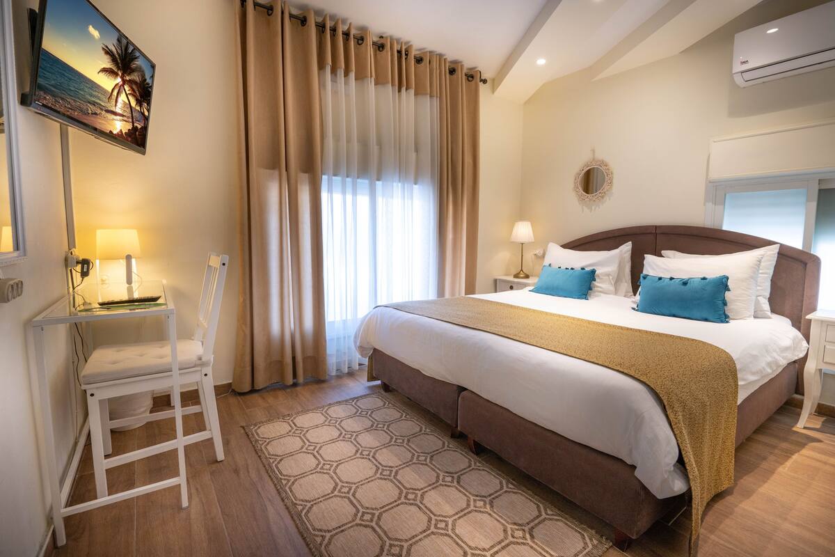 A neatly arranged bedroom with a bed, bedside tables, a chair, and a TV mounted on the wall.