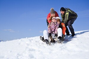 A snowy landscape with a group of people sledding.