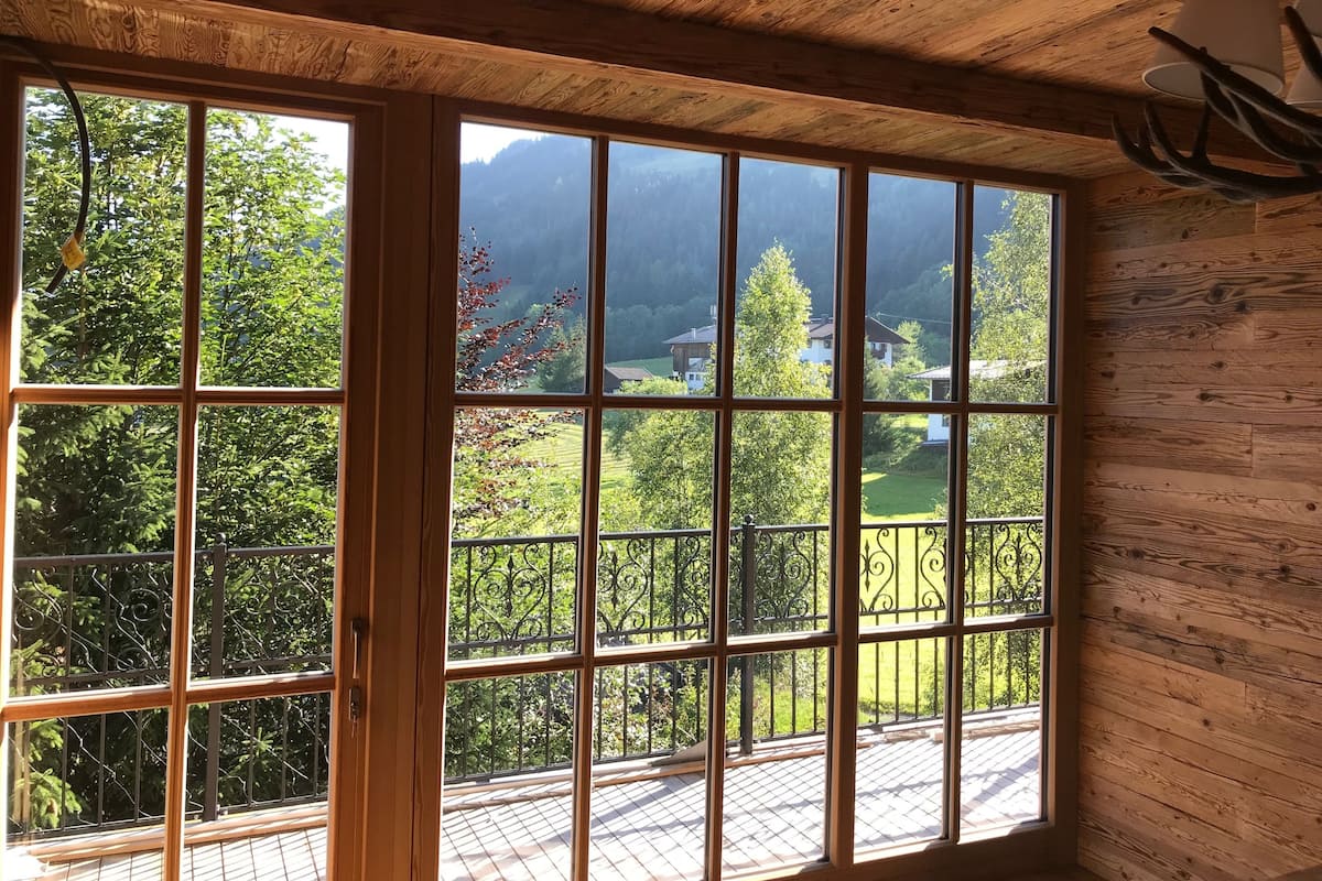 Quarto com grandes janelas, teto de madeira e varanda com grade de metal.