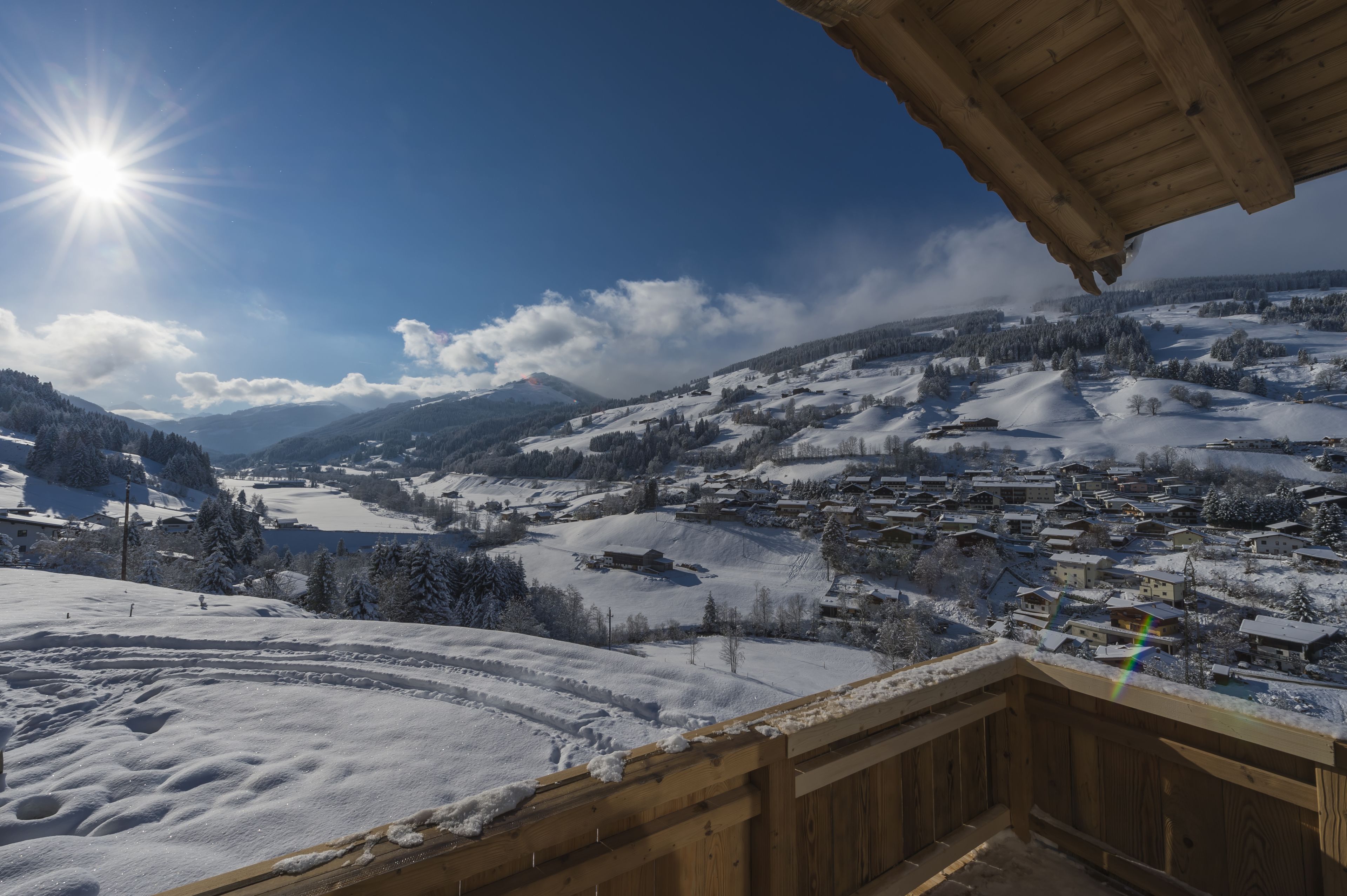 A snowy landscape with a wooden balcony overlooking a village.