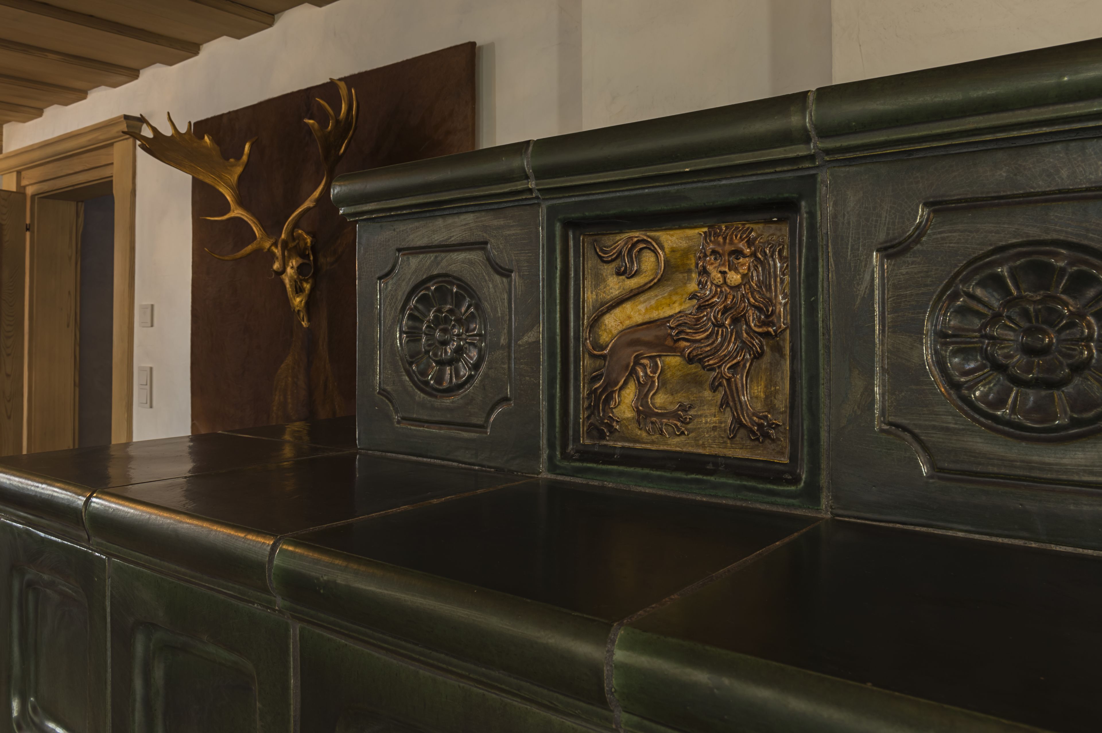 Un panel de madera oscura con detalles decorativos, incluyendo un cráneo de ciervo y un león.