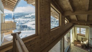 Een houten interieur met grote ramen met uitzicht op een besneeuwd landschap.