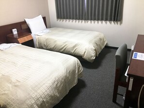 A hotel room with two single beds, a wooden nightstand, a desk, and a chair.