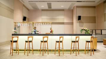 A bar area with a counter, four wooden bar stools, and a display of wine glasses.