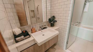 A modern bathroom with a large sink, a glass shower enclosure, and a mirror above the sink.