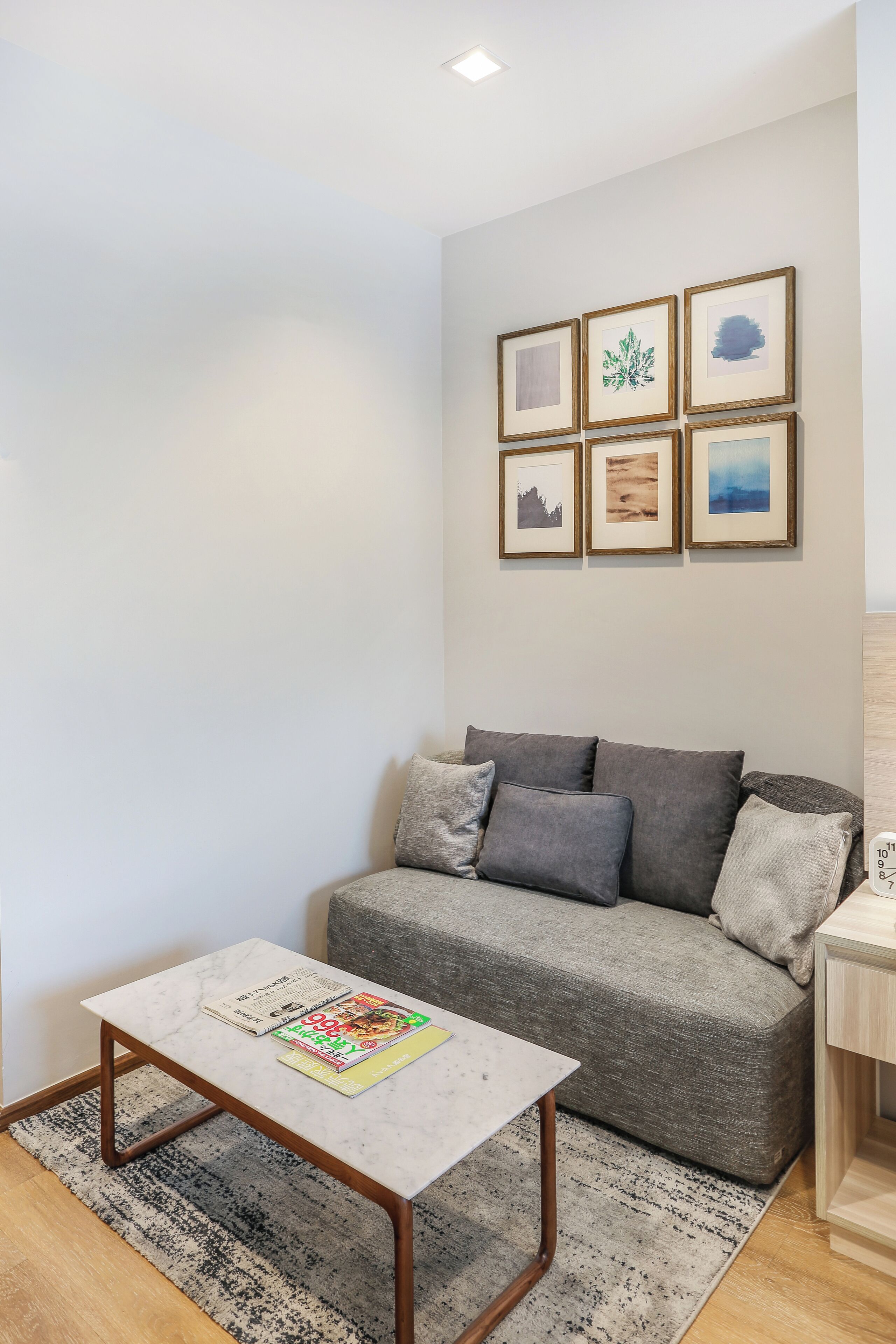 Ein Wohnzimmer mit grauem Sofa, einem Couchtisch und einer Wand mit gerahmten Bildern.
