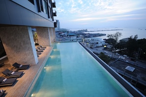A rooftop infinity pool with a view of the city and the sea.
