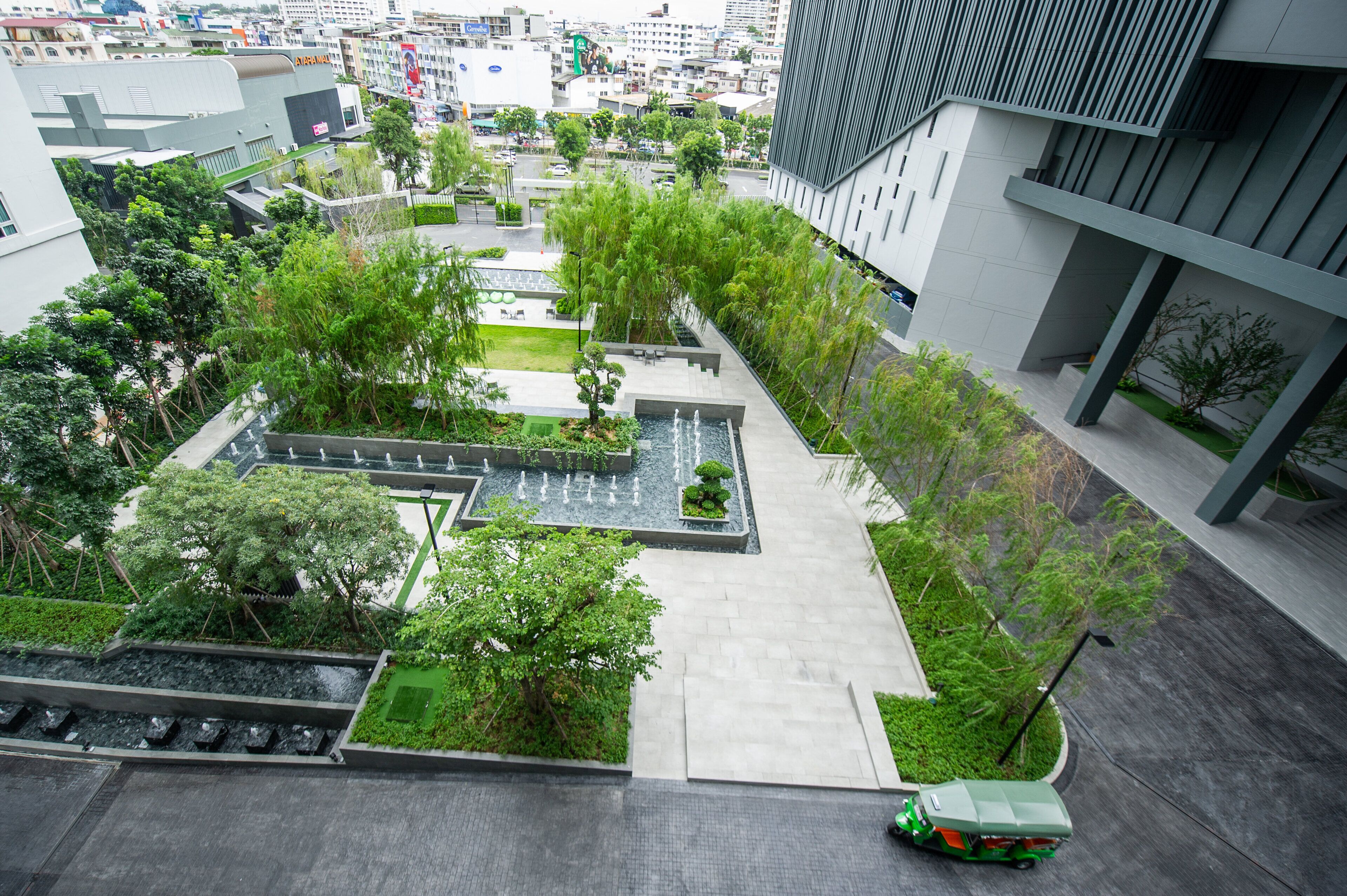 A modern urban plaza with green spaces, water features, and contemporary architecture.
