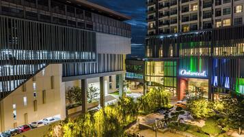A modern hotel with a prominent 'Oakwood' sign, outdoor seating, and a well-lit parking area.