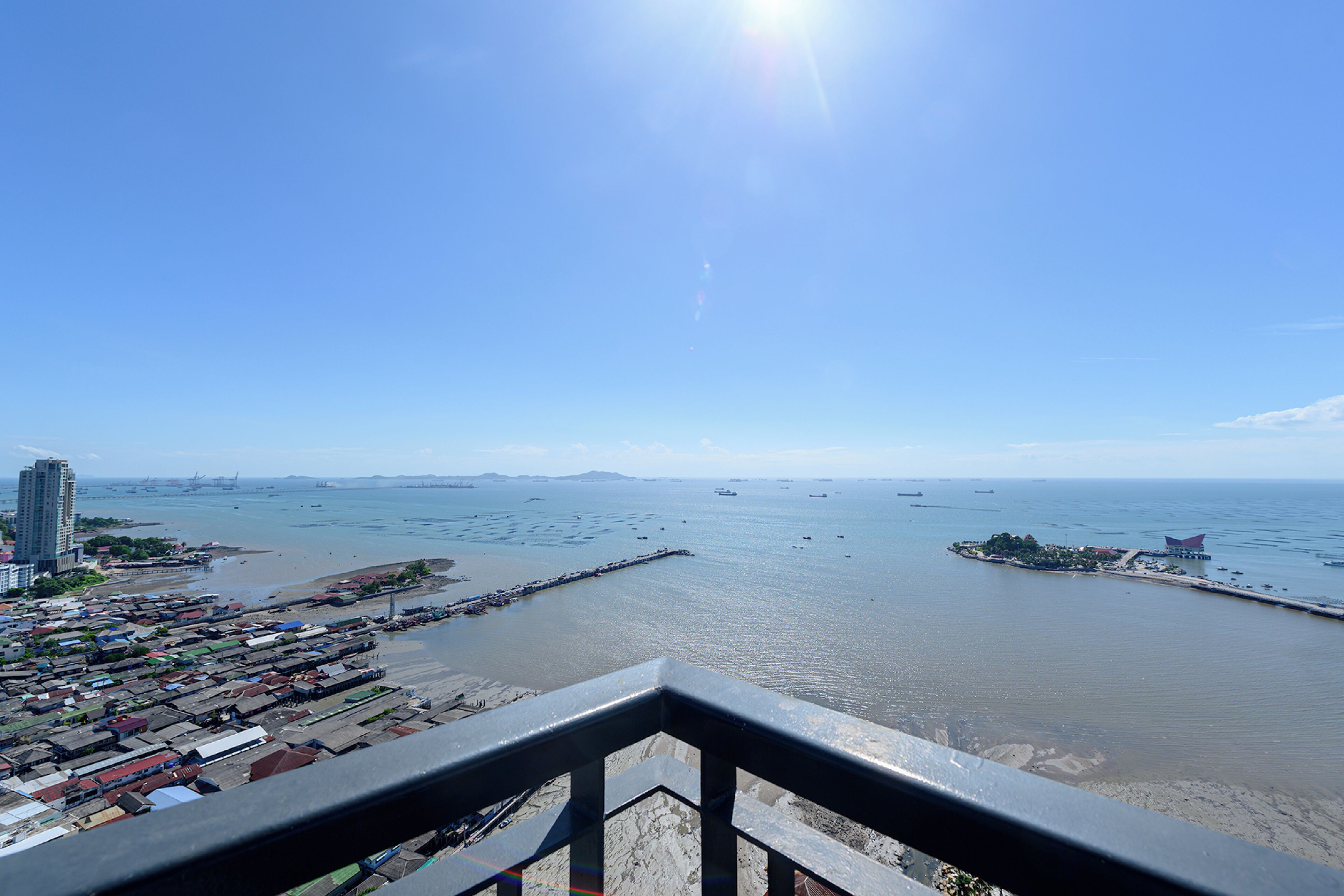 Un paisaje urbano costero con vista despejada al mar, un puente y una zona densamente poblada con edificios.