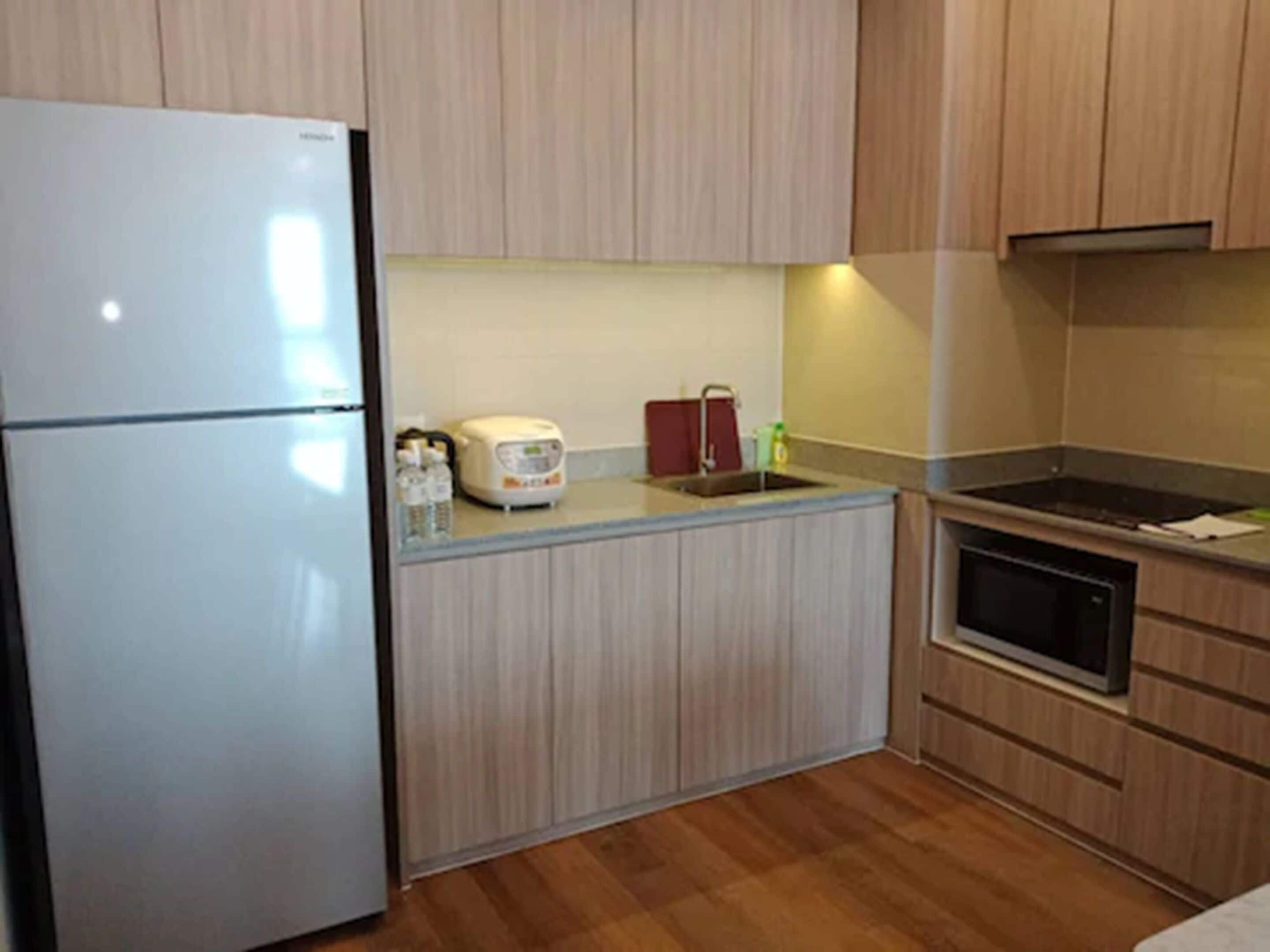 A compact kitchen with a refrigerator, a microwave, a sink, and a stove.