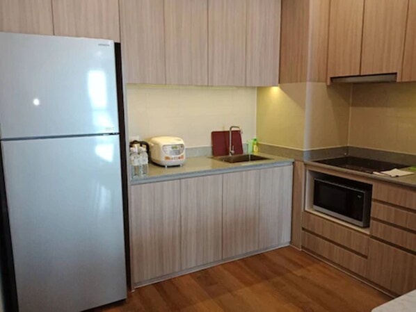 A compact kitchen with a refrigerator, a microwave, a sink, and a stove.