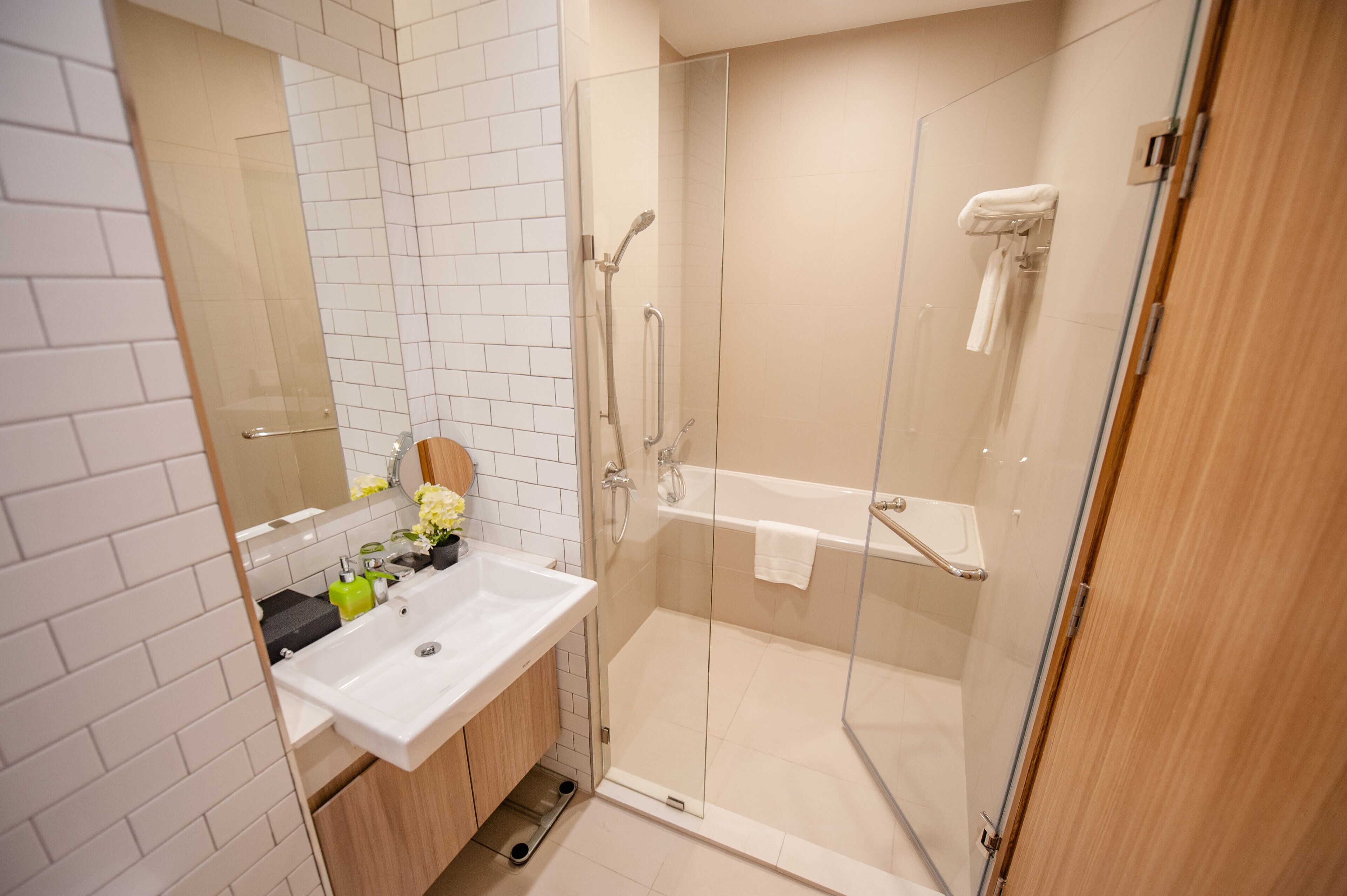Ein modernes Badezimmer mit einer Duschkabine aus Glas, einem weißen Waschbecken und einer Holzkommode.