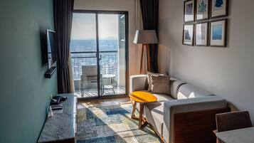 A hotel room with a balcony, a sofa, a small table, a lamp, and framed pictures on the wall.