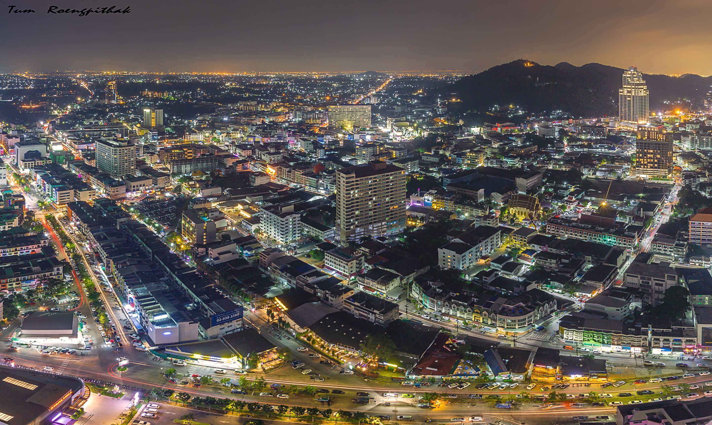 A nighttime aerial view of a densely built cityscape with numerous illuminated buildings and streets.