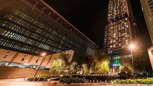 A modern hotel with a prominent glass facade and a well-lit entrance area with trees and a fountain. - Oakwood hotel & Residence Sri Racha (Si Racha)