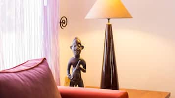 A room with a red sofa, a lamp, and a small statue.