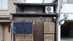 Een traditioneel Japans gebouw met een houten gevel, een schuifpoort en een airconditioningunit op het dak.