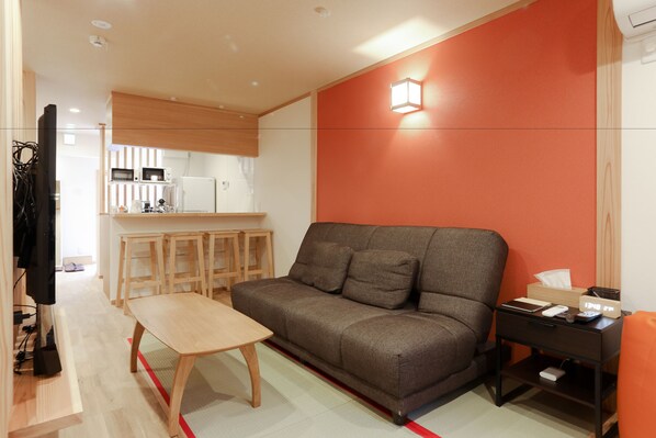 A modern living room with a sofa, a wooden coffee table, and a small side table with a lamp.