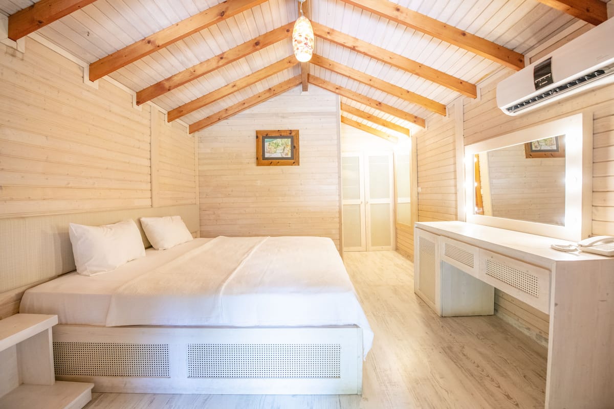 Ein Schlafzimmer einer Holzhütte mit einem Bett, einem Nachttisch und einem Schreibtisch mit Spiegel.