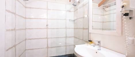 Un baño con lavamanos blanco, espejo y ducha.