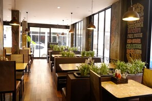 Interior de restaurante con cabinas, mesas, lámparas colgantes y una pared con el menú.
