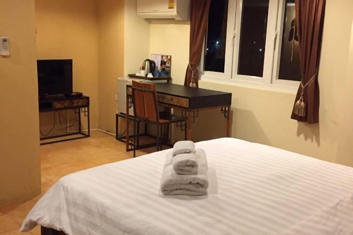 A hotel room with a bed, a desk, and a chair.