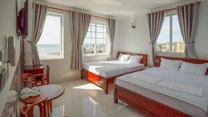A hotel room with two beds, a dining area, and large windows offering a view of the sea. - Phu Hong Hotel (Phu Quoc)