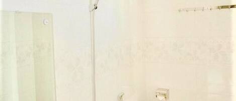 A bathroom with a mirror, a shower, and a toilet.